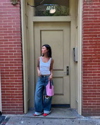 Woman in white tank, jeans, and pink bag.