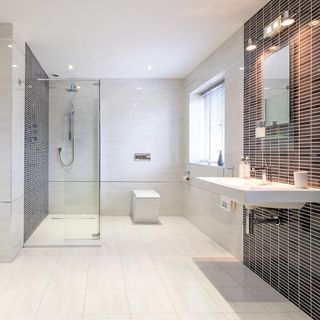 Modern black and white bathroom with big glass shower and white square toilet on off-white tiles