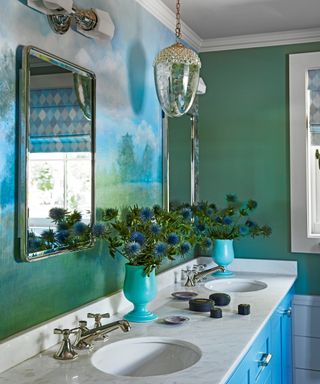 green and blue bathroom with mural, blue washstand with marble countertop, mirror and silver acorn pendant