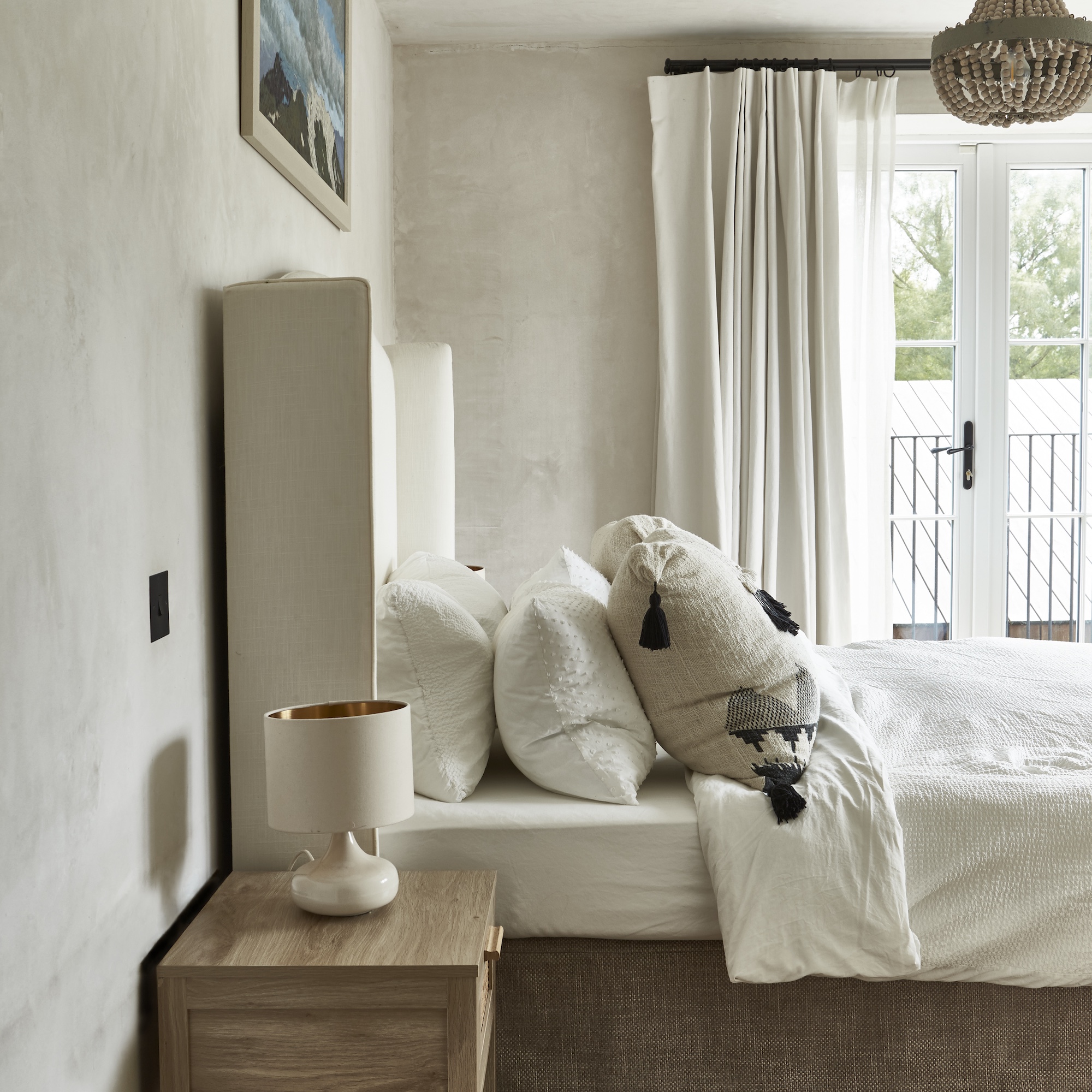 bedroom with lime plaster walls and bed with high white headboard on wooden bed