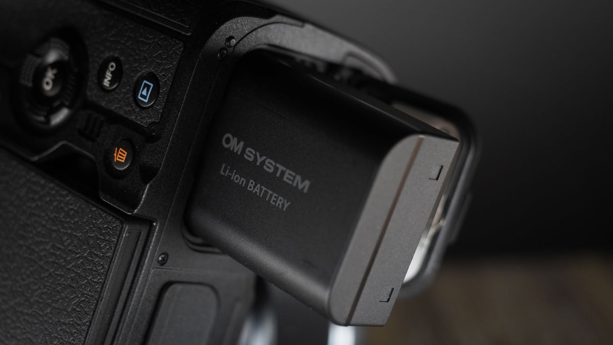 OM System OM-1 Mark II on a wooden surface, against a dark background