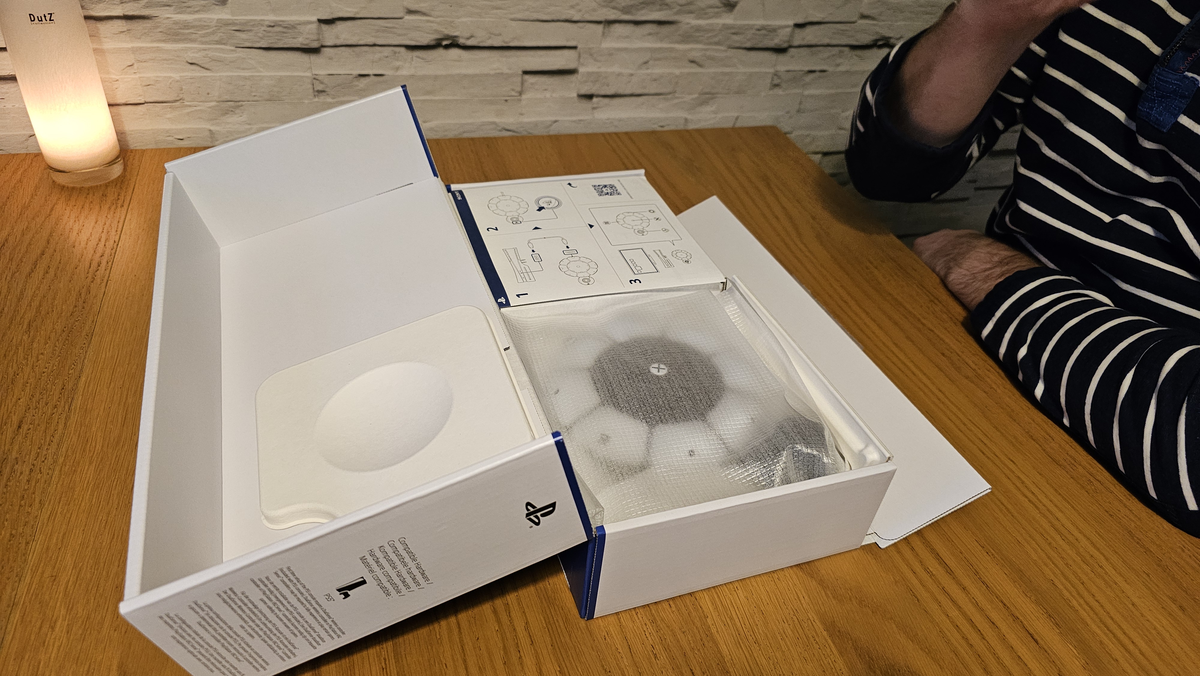 Unboxing the PlayStation Access controller with one hand on a wooden surface