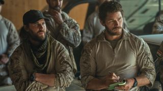 From left to right: Taylor Kitsch standing with his arms crossed and Chris Pratt writing on a notepad in The Terminal List: Dark Wolf.