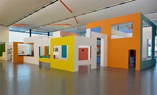 An exhibition space split into various sections, each with their only colour scheme and window and door cutouts.