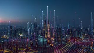 A cityscape at night with data streams riding into the sky