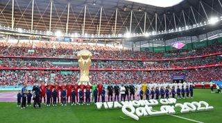 Players of Tunisia and Denmark line up on the pitch under a giant World Cup trophy prior to the FIFA World Cup Qatar 2022 Group D match between Denmark and Tunisia at Education City Stadium on November 22, 2022 in Al Rayyan, Qatar.