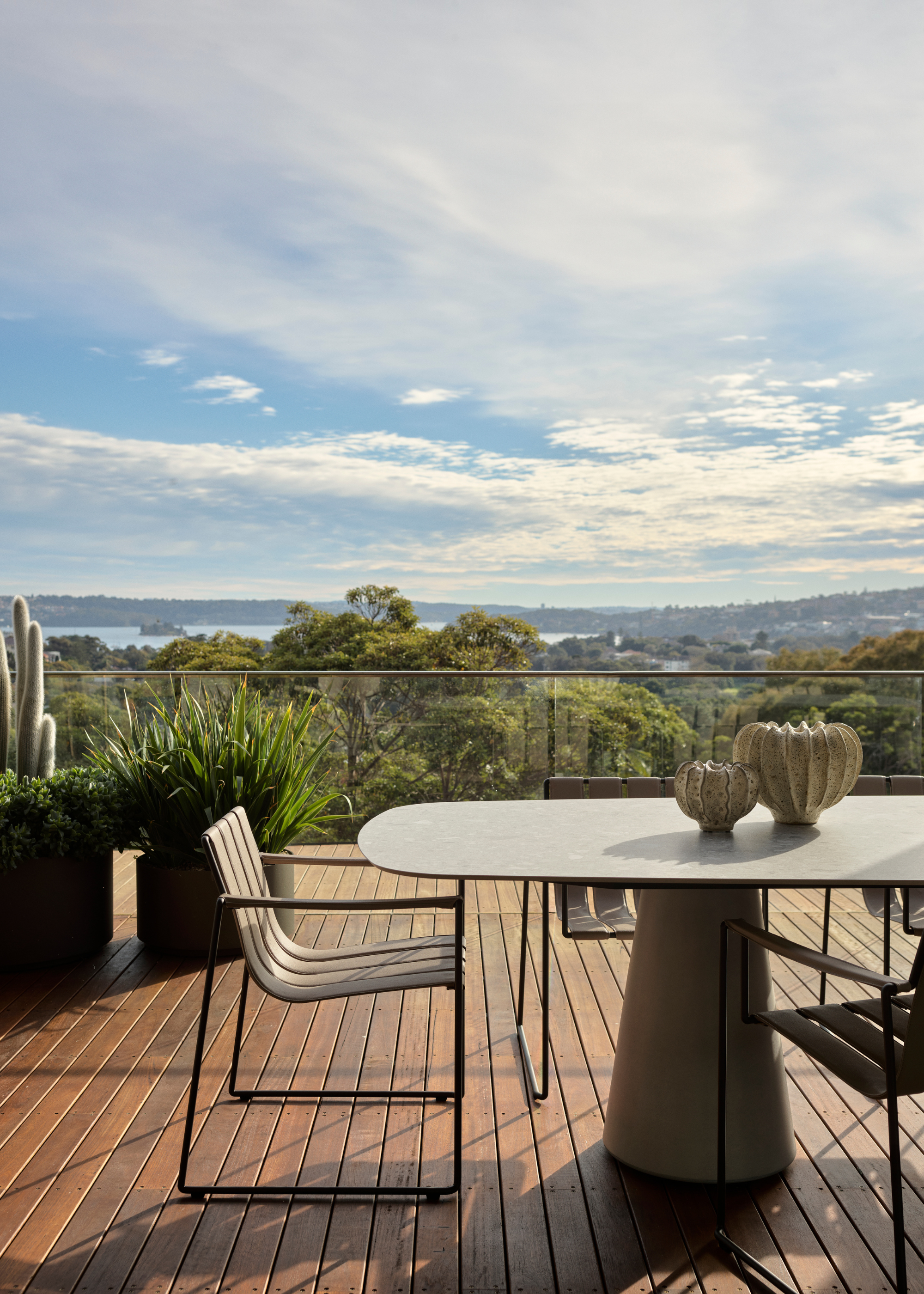 A balcony with potted foliage, an outdoor furniture set and vases