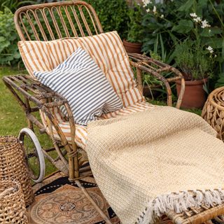 Rattan recliner with cushions and throw