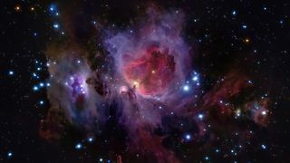 Deep-sky image of a purple and pink nebula surrounded by vibrant blue stars