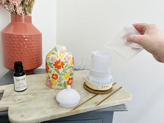Water being poured from a jug into the tank of an essential oil diffuser