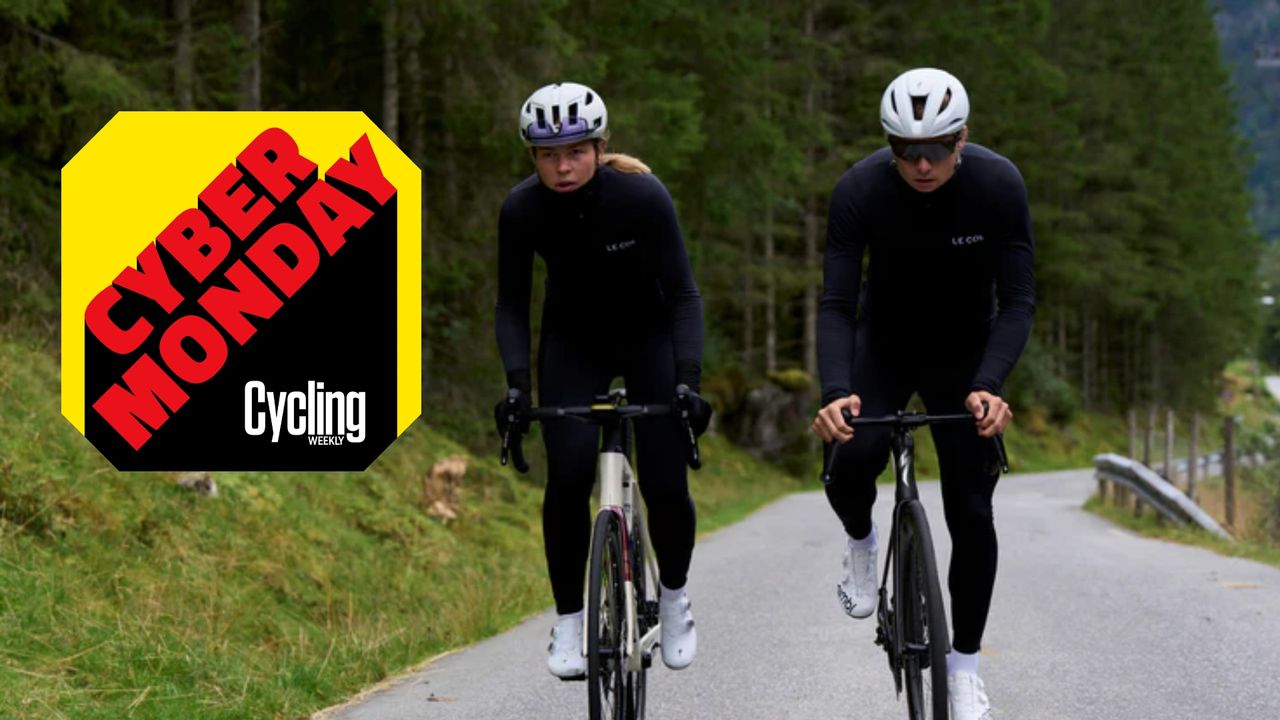 A female and male ride next to each other in Winter Le Col clothing on an alpine pass