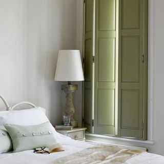 bedroom with table lamp and olive green shutters