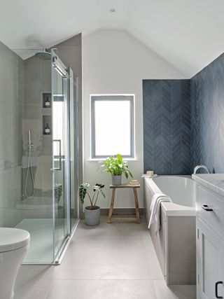White bathroom with grey tiles in shower enclosure and blue chevron tiles over the bath