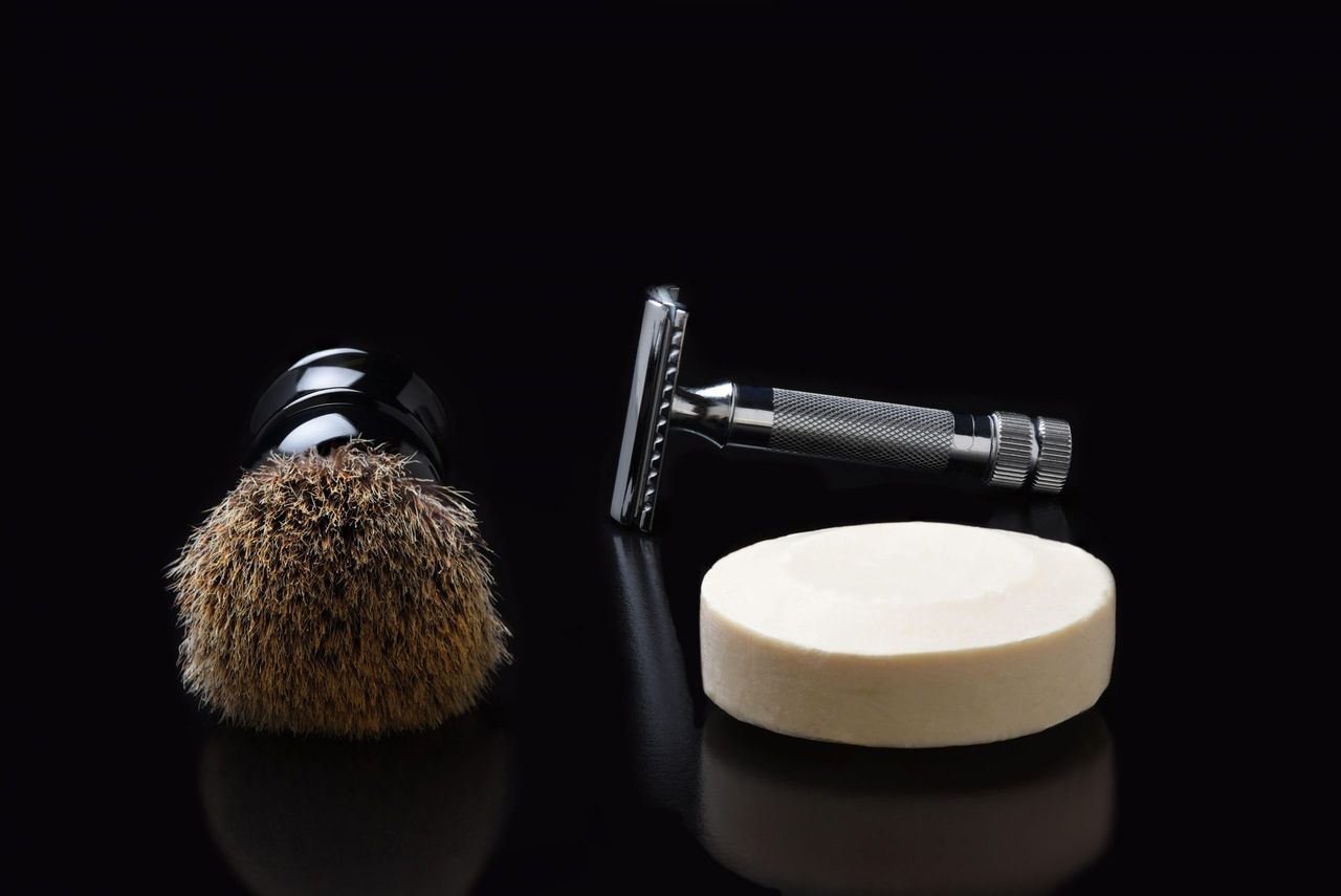 Shaving still life. A razor shaving brush and bar of soap on black.