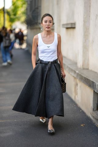 woman wears maxi pleated skirt white tank top and ballet flats