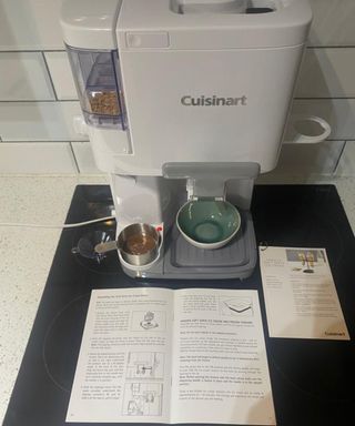Cuisinart Soft Serve Ice Cream Maker with recipe card, instruction booklet, warming cup with chocolate sauce, and crushed nuts in topping compartment