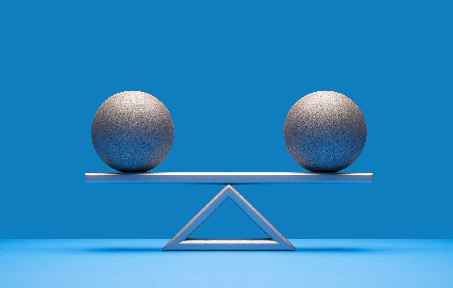 two silver balls equally balanced on seesaw weight scale