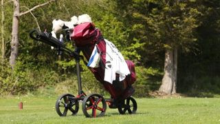 PowaKaddy DLX Lite FF Push Cart resting on the fairway showing off its three wheel design