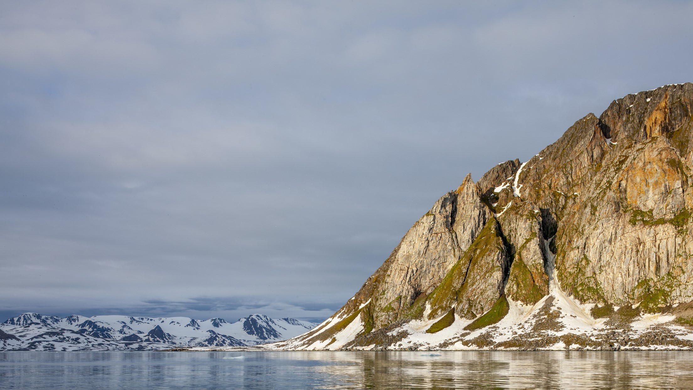 serene landscape with large rocky outcrops and snow-covered landscape with still water below.