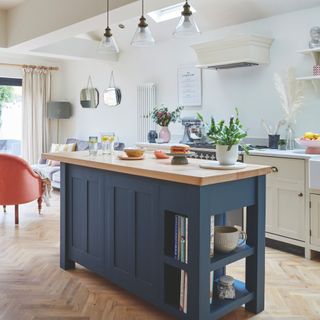 Cream kitchen with a blue wooden kitchen island in the middle