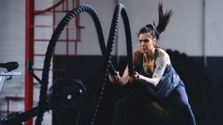 Woman performs battle rope slam