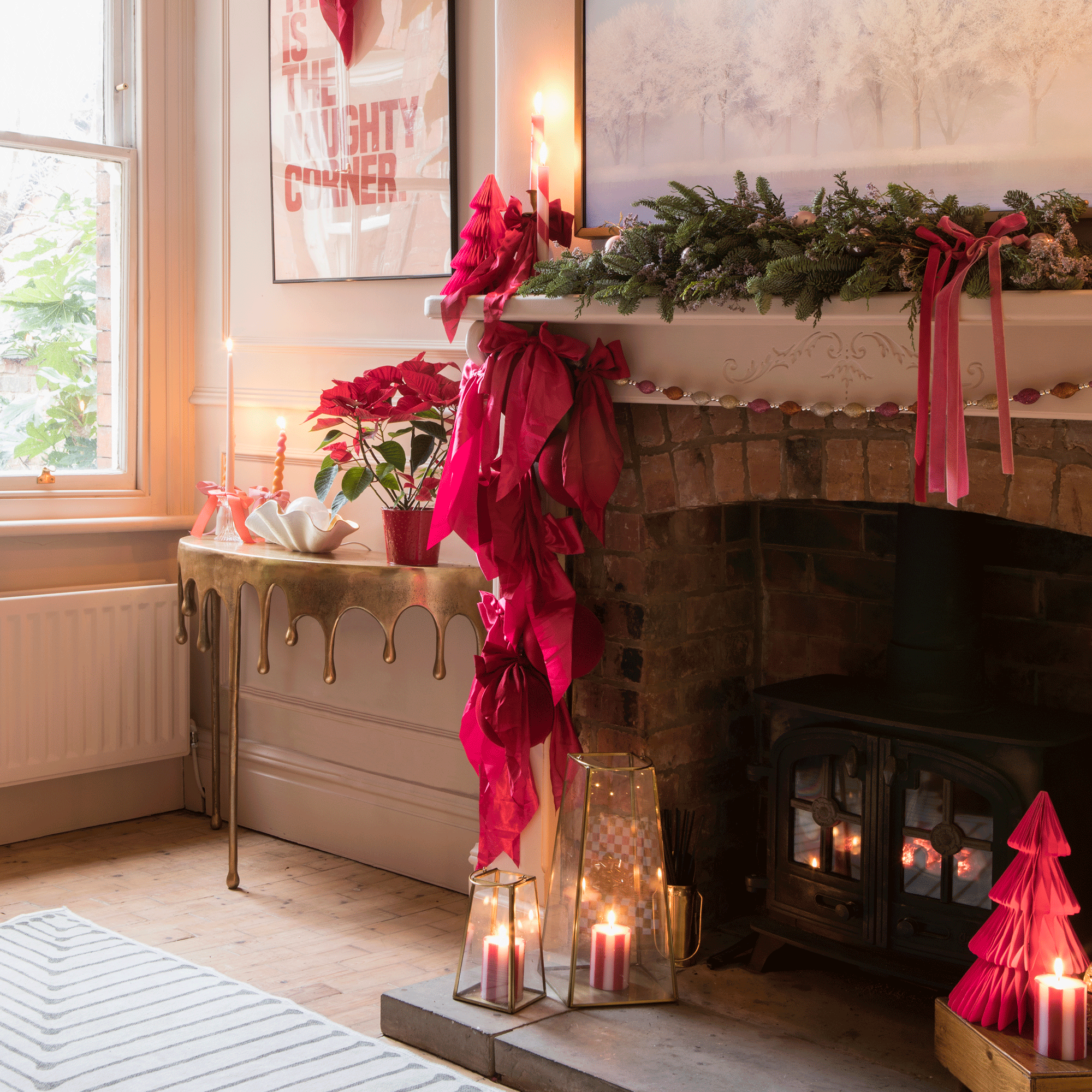 a living room with fireplace and mantelpiece covered in festive greenery and red velvet bows