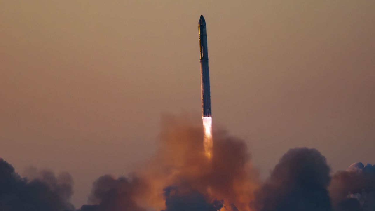a massive rocket lifts off above a plume of fire at sunrise
