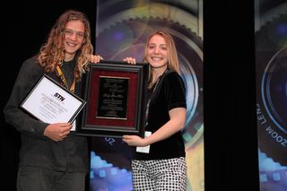 Two students hold up framed awards for broadcasting