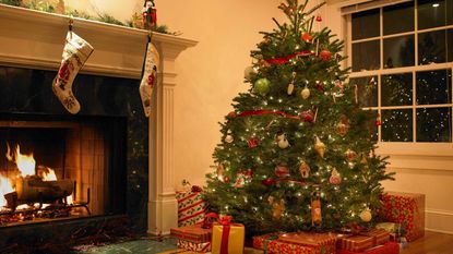 Christmas tree in living room with presents in front of a fireplace