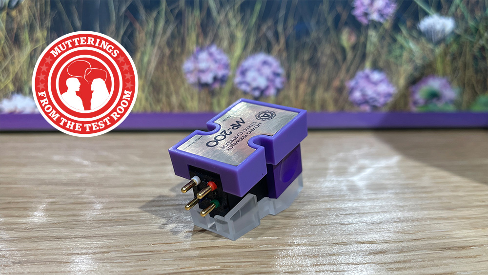 A purple Nagaoka cartridge on a desk with a purple flower wallpaper background