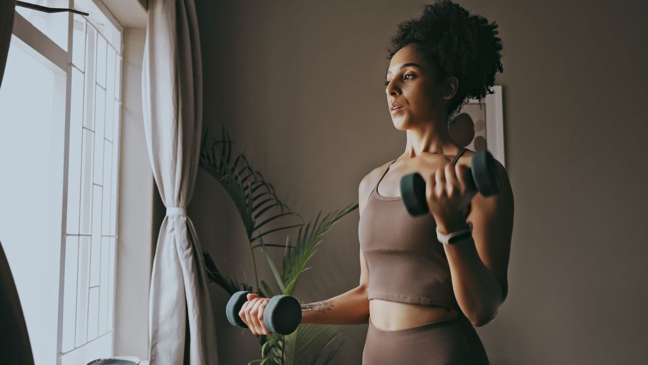 A woman completing a dumbbell workout at home