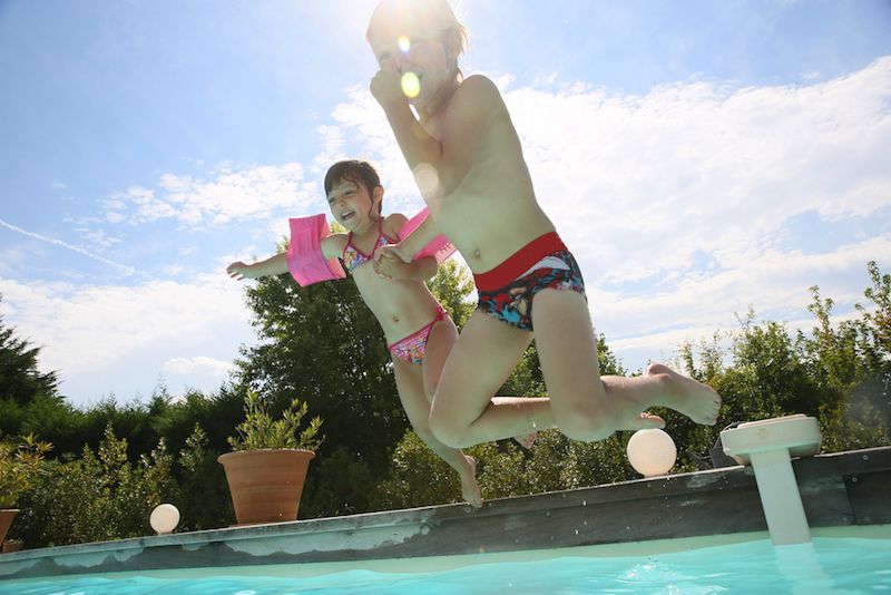 Children jump into a swimming pool.