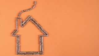 orange background with wooden pellets arranged in shape of a house