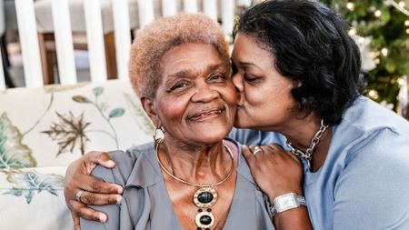 Adult daughter embraces her smiling elderly mother 