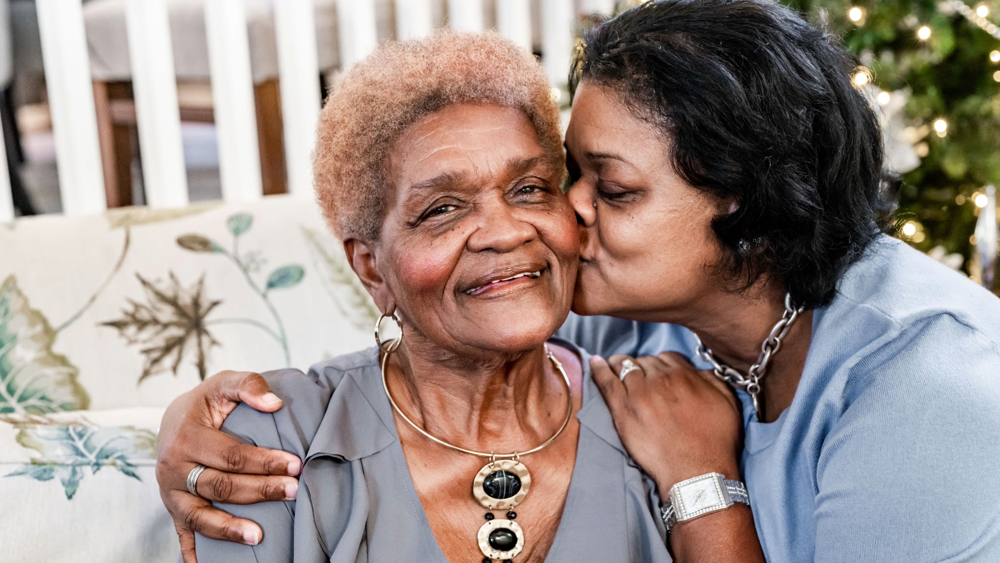 Adult daughter embraces her smiling elderly mother 