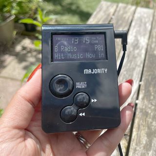 Majority Petersfield Go DAB radio held in hand above wooden outdoor table