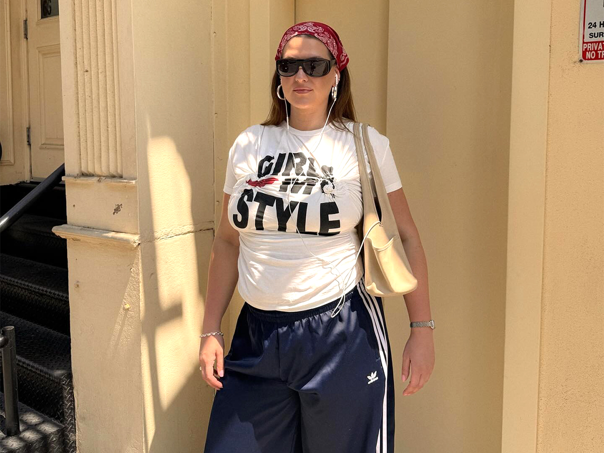 Influential man Raeann Langas wears adidas track pants with graphic t-shirt and black sunglasses.