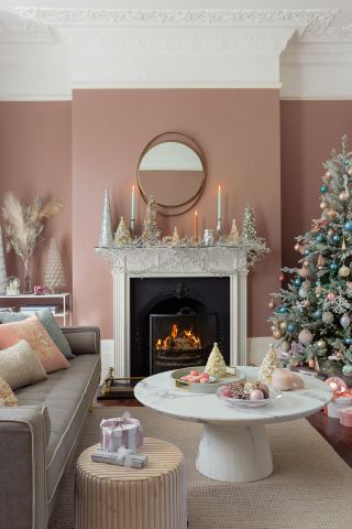 pink living room with pastel color decorations, a Christmas tree, pastel candlesticks and a gold mirror