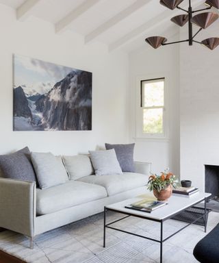 White dining room with vaulted ceiling, gray sofa, marble coffee table, artwork on wall