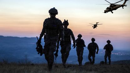 military people walking with helicopter in background