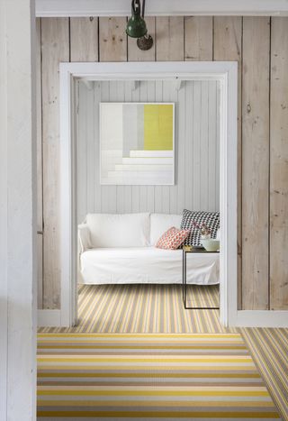 A stripy yellow carpet with a perpendicular striped rug on top