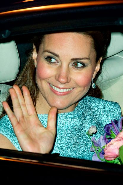 Kate Middleton wears a green dress and holds flowers as she's driven away