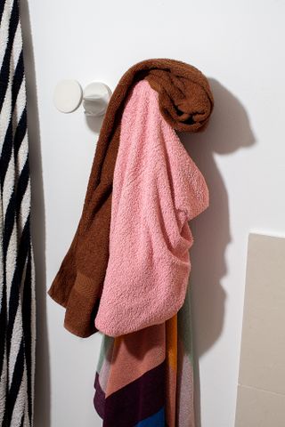 Different coloured towels hanging on a wall towel hanger.