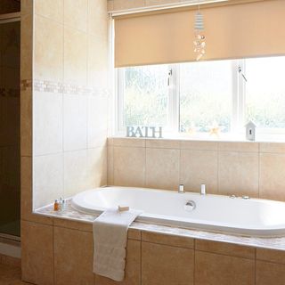 bathroom with cream tiles and white bathtub