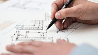 A person drawing an architectural design by hand.