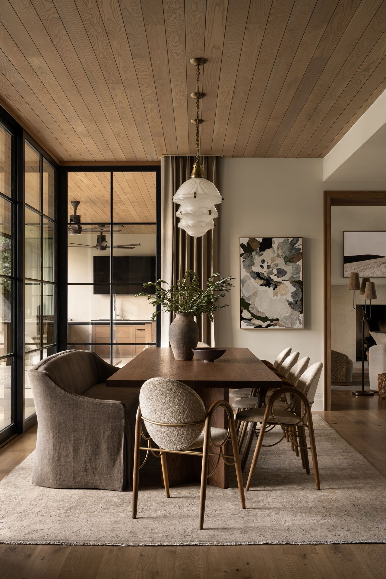 An upholstered bench and Danish armchairs surround a wooden dining table