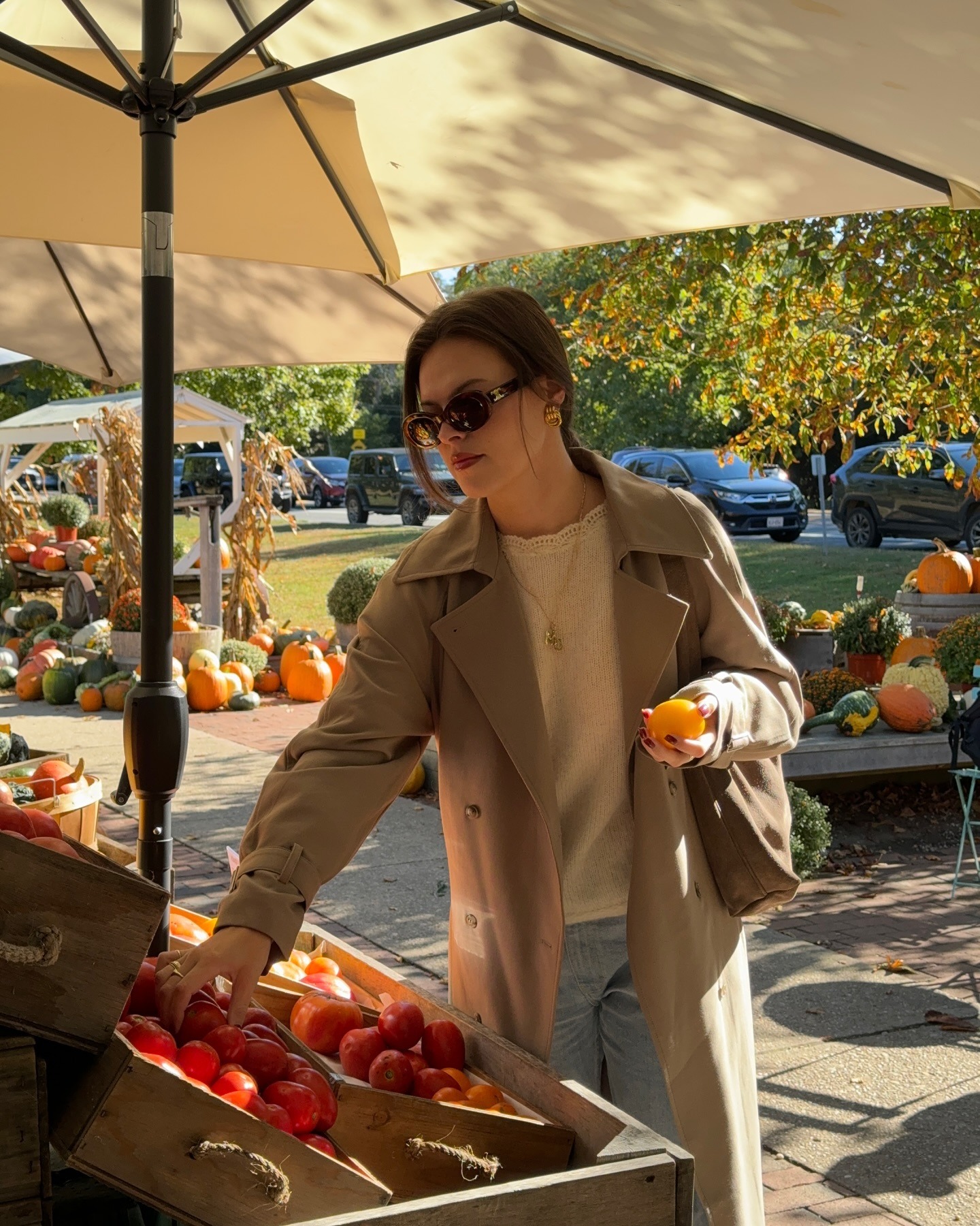 A woman picking out produce from a farmer&#039;s market stand.
