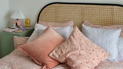 Pink throw pillows on bed with rattan headboard