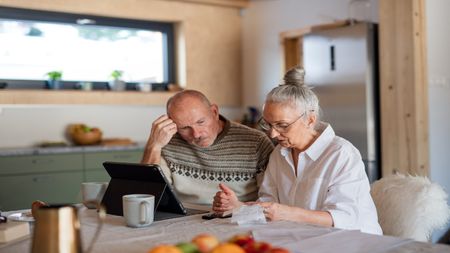 Older couple, man and woman, looking at receipts and computer