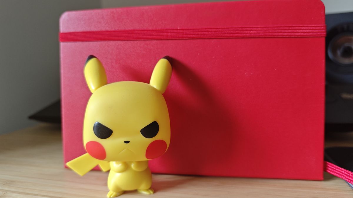 Image of a Pikachu Pop Vinyl figure against a red notebook shot on a Poco F7 Pro phone